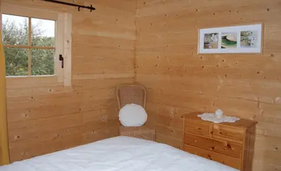 a bedroom with a bed and a chair and a window at chalet climatisé Porticcio Corse in Fontanaccio