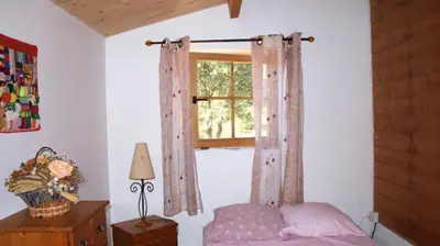 a bedroom with a bed and a window with curtains at chalet climatisé Porticcio Corse in Fontanaccio