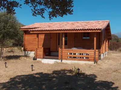 a log cabin with a porch in a field at chalet climatisé Porticcio Corse in Fontanaccio