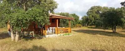 a wooden cabin with chairs in a field at chalet climatisé Porticcio Corse in Fontanaccio