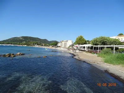 a beach with rocks in the water and buildings at Résidence Coté Plage in Sainte-Lucie de Porto-Vecchio