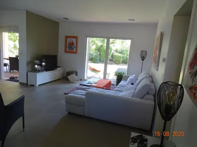 a living room with a white couch and a television at Résidence Coté Plage in Sainte-Lucie de Porto-Vecchio