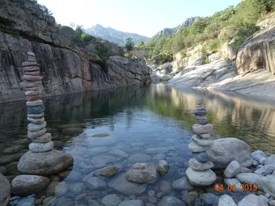 a river with stacks of rocks in the water at Résidence Coté Plage in Sainte-Lucie de Porto-Vecchio