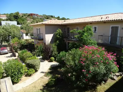 a garden in front of a house with flowers at Résidence Coté Plage in Sainte-Lucie de Porto-Vecchio