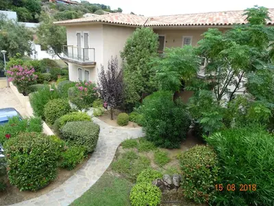 a garden in front of a house with bushes and trees at Résidence Coté Plage in Sainte-Lucie de Porto-Vecchio