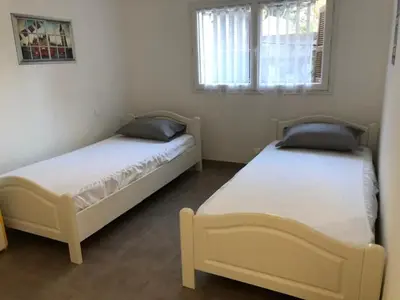 a bedroom with two beds and a window at Villa Lucie Paul rez de jardin à Méla in Mela
