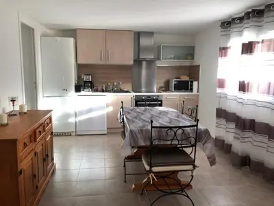 a kitchen with a table and a chair in it at Villa Lucie Paul rez de jardin à Méla in Mela