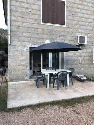 a table and chairs under an umbrella next to a building at Villa Lucie Paul rez de jardin à Méla in Mela