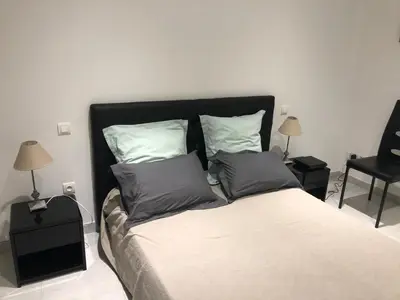 a bedroom with a bed with two pillows and a chair at Au cœur de la cité médiévale avec petite vue mer in Bonifacio