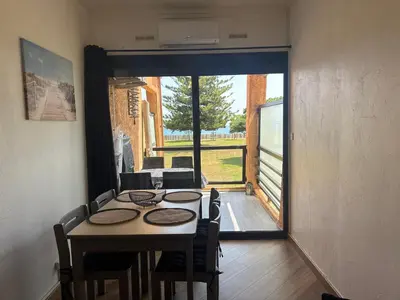 a dining room with a table and chairs and a sliding glass door at Appartement n 216 Moriani plage in Santa-Lucia-di-Moriani