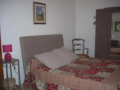 a bed with a quilt and a chair in a bedroom at Demeure traditionnelle en pierre avec piscine in Sartène