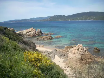 a view of a beach with rocks and the ocean at Demeure traditionnelle en pierre avec piscine in Sartène