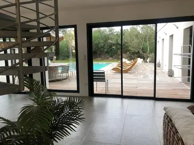 a living room with sliding glass doors leading to a pool at VILLA LECCI E MARE in Olmucciu
