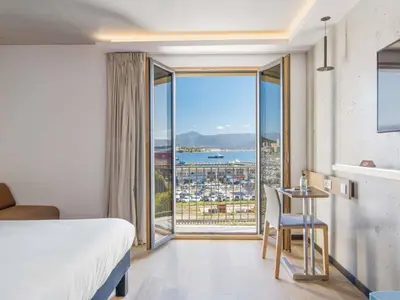 a hotel room with a bed and a view of the ocean at ibis Styles Ajaccio Napoleon in Ajaccio