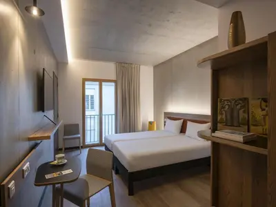 a hotel room with a bed and a desk and a window at ibis Styles Ajaccio Napoleon in Ajaccio