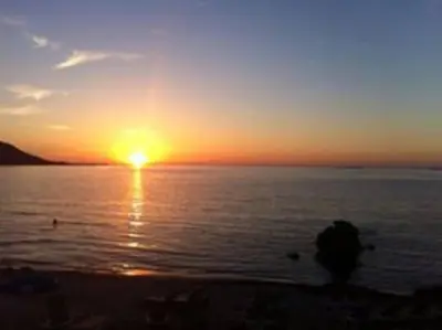 a sunset over a body of water with the sun setting at PIETROSELLA Plage du RUPIONE in Pietrosella