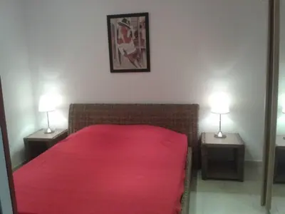 a bedroom with a bed with a red blanket and two lamps at PIETROSELLA Plage du RUPIONE in Pietrosella