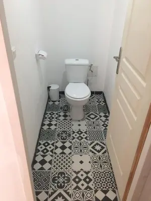 a bathroom with a toilet and a black and white tile floor at Fresi Gustave in Levie