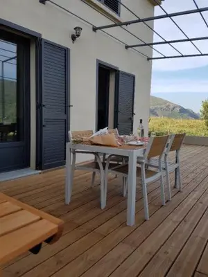 a white table and chairs on a wooden deck at Entre mer et montagne, en plein maquis in Vallecalle