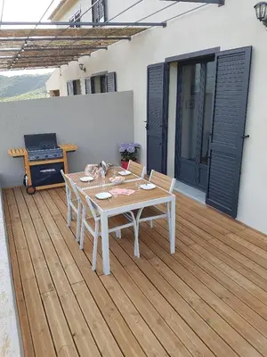 a white table and chairs on a wooden deck at En plein maquis,entre mer&montagne in Vallecalle