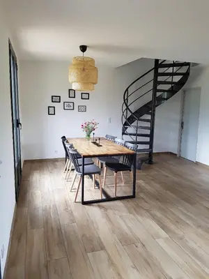a dining room with a table and chairs and a spiral staircase at En plein maquis,entre mer&montagne in Vallecalle