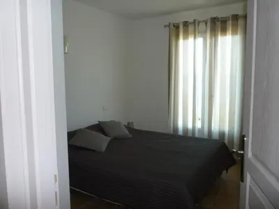 a bedroom with a black bed and a window at APPARTEMENT PIED DANS L EAU ET VUE MER MAGNIFIQUE in Sartène