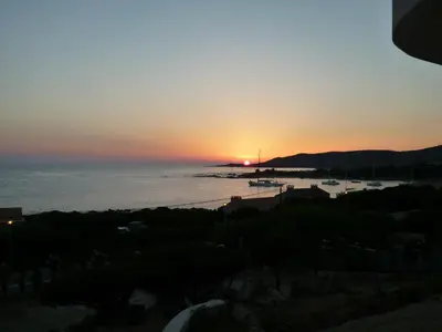 a sunset over the ocean with boats in the water at APPARTEMENT PIED DANS L EAU ET VUE MER MAGNIFIQUE in Sartène