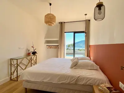 a bedroom with a bed and a large window at Villas de standing avec magnifique vue mer et piscines privées, Sagone in Sagone
