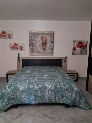 a bedroom with a bed with a green comforter at Villa Giuseppina in Bonifacio
