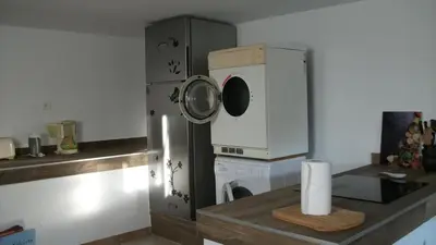 a kitchen with a refrigerator and a washing machine at T2 dans la région Bastiaise vue sur la mer in Furiani