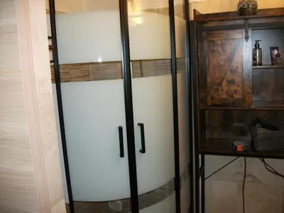 a glass and steel closet with a wooden cabinet at T2 dans la région Bastiaise vue sur la mer in Furiani