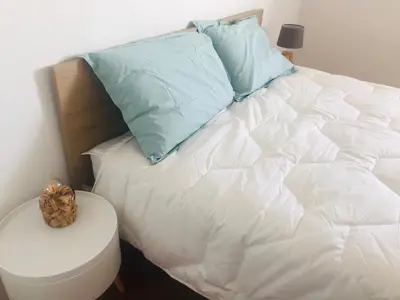 a white bed with blue pillows on top of it at Superbe appartement 3 étoiles Ajaccio début Sanguinaires in Ajaccio