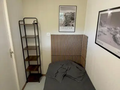 a small bedroom with a bed and a shelf at Marina di pinarello, appt climatisé à 400m de la plage in Zonza