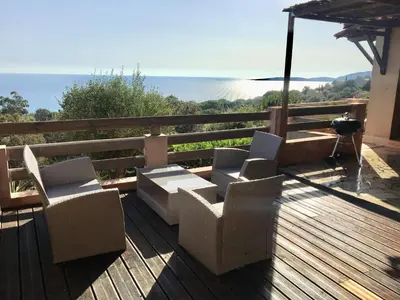 a deck with two chairs and a table and an umbrella at Residence du valinco Appartement in Olmeto