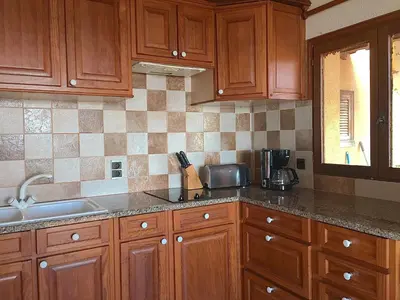 a kitchen with wooden cabinets and a sink at Residence du valinco Appartement in Olmeto