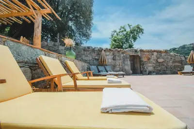 a patio with two lounge chairs and a stone wall at Résidence de Luxe 4 étoiles à Pietralba, 4 logements piscine chauffée BALAGNE in Pietralba
