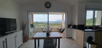 a living room with a table and a clock on the wall at Très belle Résidence vue mer et piscine chauffée - BACCALOCATION in Porto-Vecchio