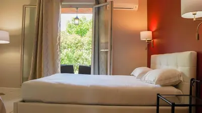 a bedroom with a bed and a window at Hôtel Les Jardins in Lucciana