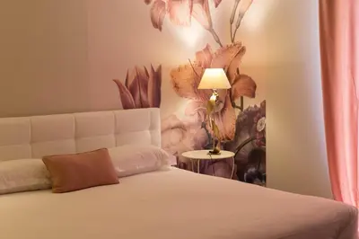 a bedroom with a bed with a flower mural on the wall at Hôtel Les Jardins in Lucciana