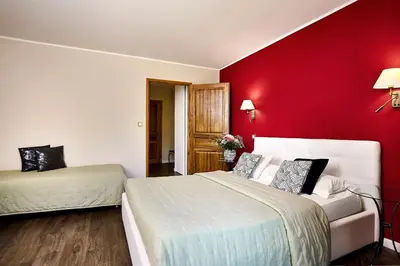 a bedroom with two beds and a red wall at Hôtel Les Jardins in Lucciana