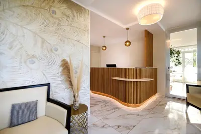 a lobby with a wall with a wooden desk at Hôtel Les Jardins in Lucciana