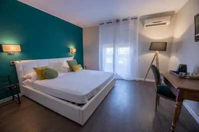 a bedroom with a white bed and a desk and a desk at Hôtel Les Jardins in Lucciana