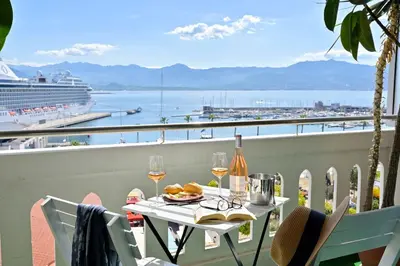 a table on a balcony with a view of a cruise ship at Hôtel Du Golfe in Ajaccio