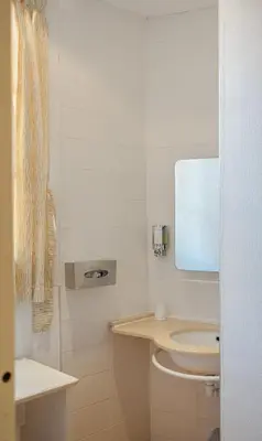 a bathroom with a white toilet and a sink at Hôtel Du Golfe in Ajaccio