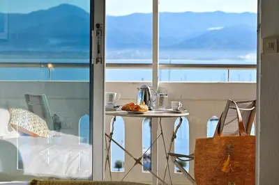 a table on a balcony with a view of the ocean at Hôtel Du Golfe in Ajaccio