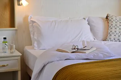 a bed with a book and pair of glasses on it at Hôtel Du Golfe in Ajaccio