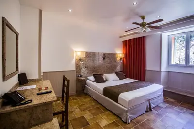 a hotel room with a bed and a desk and a bed sidx sidx sidx sidx at Les Jardins De La Glacière in Corte