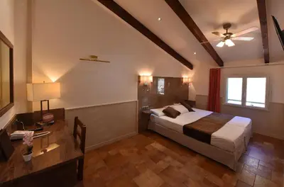a bedroom with a bed and a ceiling fan at Les Jardins De La Glacière in Corte