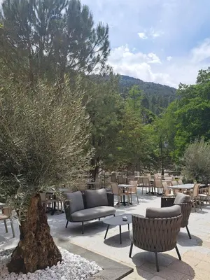 a patio with chairs and tables and a tree at Les Jardins De La Glacière in Corte