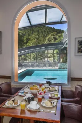 a table with food and a view of a pool at Les Jardins De La Glacière in Corte
